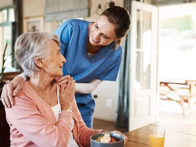 Senior housing advisor supporting elderly woman with personalized care in a comfortable home setting.