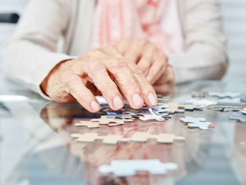 memory care advisor supporting cognitive engagement through puzzle activity for older adult