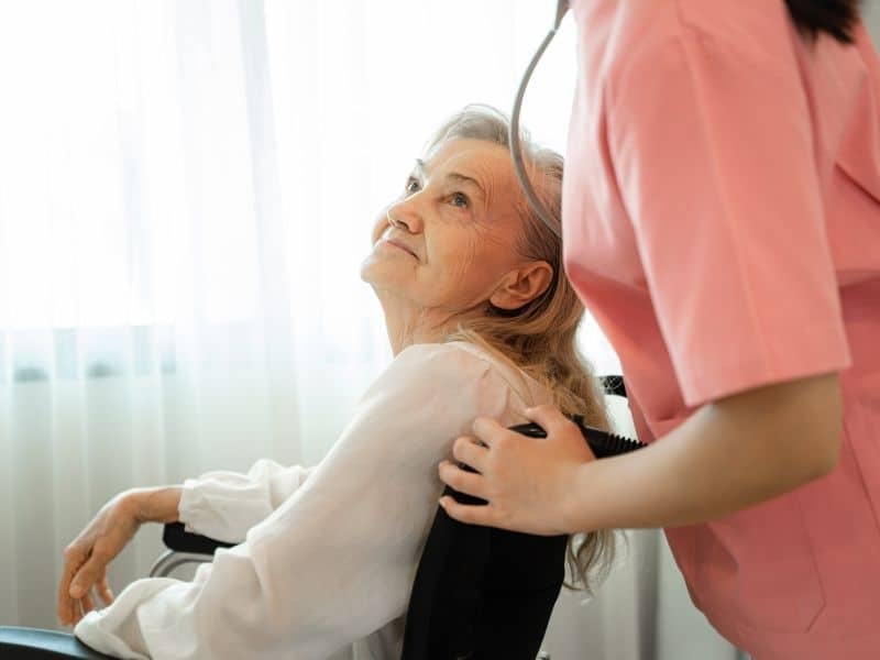caregiver assisting elderly woman in wheelchair during memory care planning services